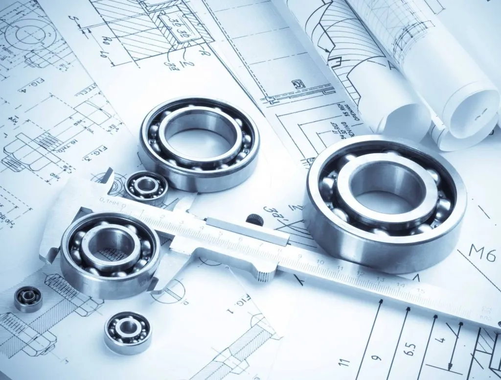 Rodamientos y calibre sobre planos de ingeniería.