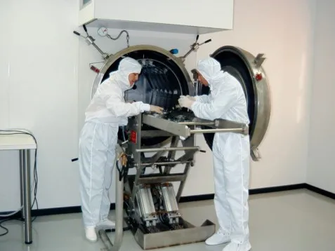 Técnicos con trajes blancos trabajando en un entorno limpio.