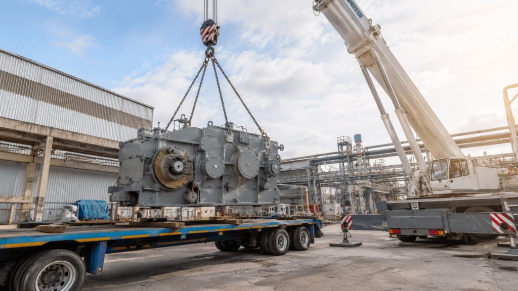 Grúa industrial elevando maquinaria pesada para su transporte en instalación industrial