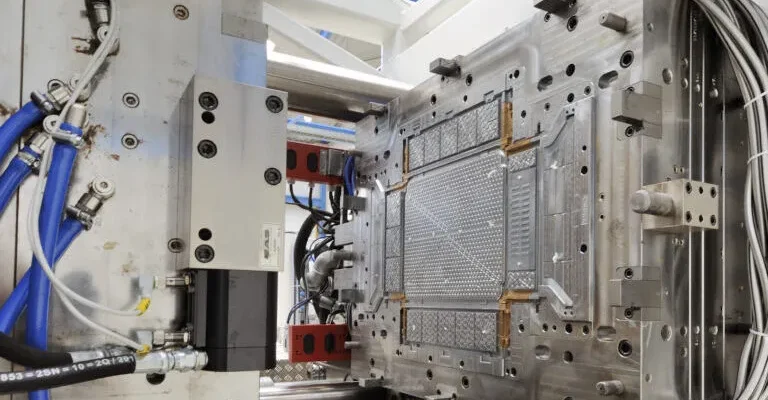 Molde metálico de inyección de plástico con cables y mangueras alrededor