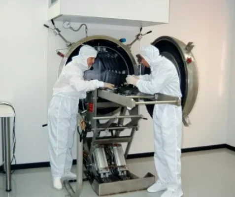 Técnicos con trajes blancos trabajando en un entorno limpio.